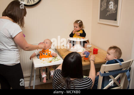 Babys und Kleinkinder mit einem Snack im Kindergarten, Großbritannien Stockfoto