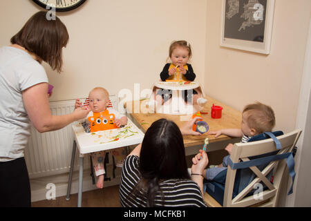 Babys und Kleinkinder mit einem Snack im Kindergarten, Großbritannien Stockfoto