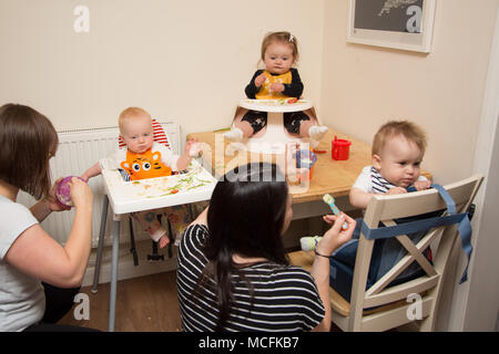 Babys und Kleinkinder mit einem Snack im Kindergarten, Großbritannien Stockfoto