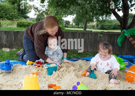 Babys spielen in einem Sandkasten Stockfoto