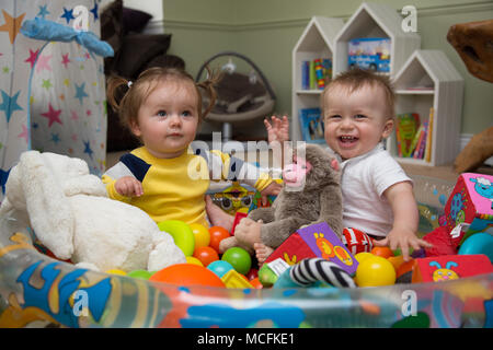 Babys, die mit ihren Spielsachen spielen. Stockfoto