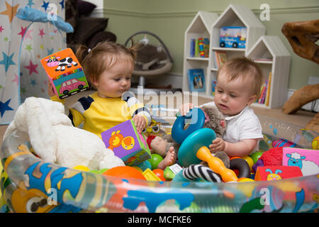 Babys, die mit ihren Spielsachen spielen. Stockfoto