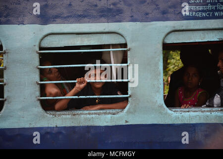 Familie in einem Zug reisen in Indien und der junge Peering aus dem vergitterten Fenster aus dem Schlitten Stockfoto