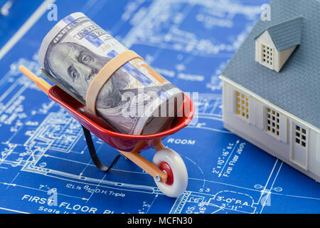 Blueprints mit einem Modell Haus und Wheel Barrow mit Geld. Stockfoto