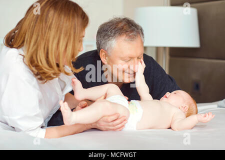 Großeltern und das Baby Spielen auf das Bett im Schlafzimmer. Stockfoto