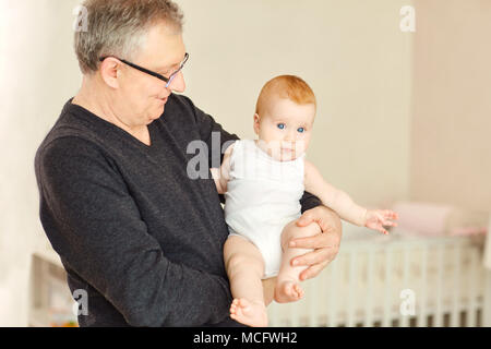 Opa mit der Enkelin ein Baby in ihren Armen im Innenbereich. Stockfoto