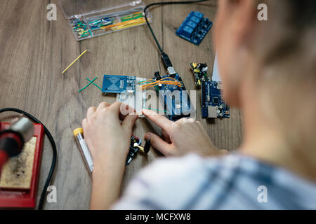 Blick von oben auf eine weibliche Hände Löten der Platine von Lötkolben auf den Tisch. Stockfoto