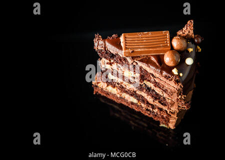 Stück leckeren Schokoladenkuchen mit cremiger inter-Layer mit Schokolade Süßigkeiten auf schwarzem Hintergrund serviert dekoriert Stockfoto