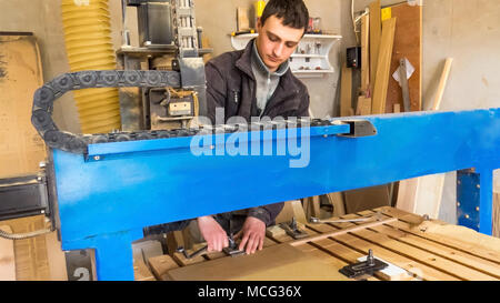 Der Arbeitnehmer Wendungen der Überwurfmutter an der CNC-Maschine. CNC-Fräsmaschine, Verarbeitung von Holz. Tischlerei, Möbel und Produkte aus Holz. Wartung Stockfoto