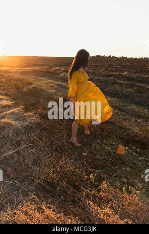 Eine Frau trägt einen gelben Kleid weht im Wind. Stockfoto
