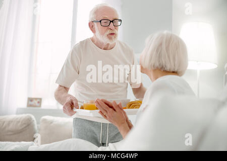 Fröhlicher älterer Mann über seine Frau Pflege Stockfoto