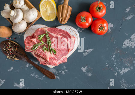 Teilstücke von Rindfleisch für das Grillen auf einem hölzernen Schneidebrett mit dem Lorbeerblatt, Rosmarin, Olivenöl und Kräutern der Provence für die Marinade in einer rustikalen Stil. A h Stockfoto