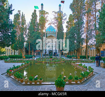 MAHAN, IRAN - Oktober 16, 2017: Die malerische Vakil-ol-molki Innenhof von Shah Nematollah Vali Schrein mit üppigen Nadelwälder Garten, polygonalen Teich und Tur Stockfoto