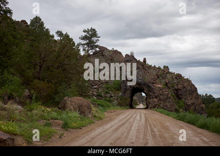 Unbefestigte Straße durch eine gewölbte Schneiden in einer Felsformation neben den Arkansas River, Colorado und Rückzug in die Ferne Stockfoto