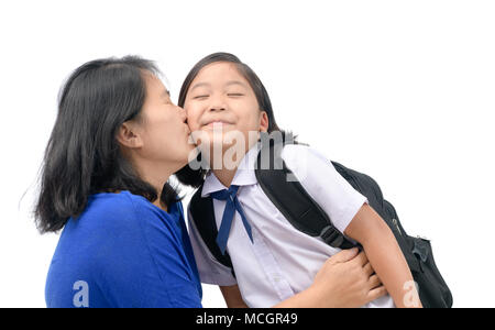 Mutter küssen ihre Tochter in Uniform Student, bevor sie zur Schule gehen, auf weißem Hintergrund, Liebe und Sorgfalt Konzept isoliert Stockfoto