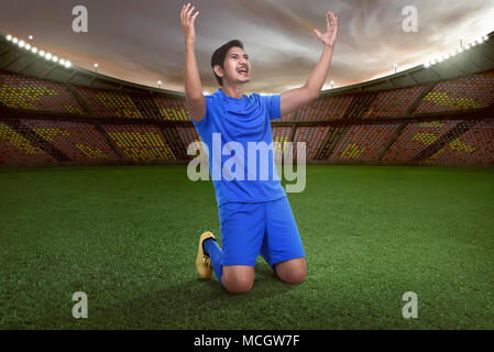 Stattliche Asian Football Player glücklich für das Gewinnen der Match auf Stadion Stockfoto