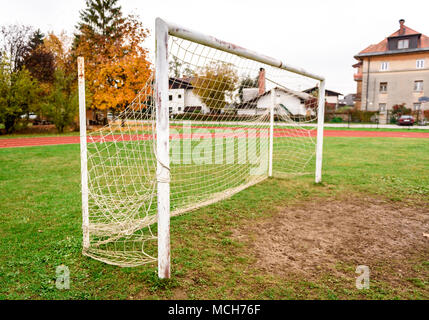 Alte freie Fußball Fußball Ziel Gate in ländlichen Rasenfläche. Alte Sportplatz mit rostigen Ziel und net auf Wiese mit schlammigen Front. Stockfoto