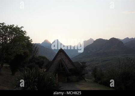 Hintergrund der Sonnenuntergang über die Drakensberge, mit der Kapelle des Cathedral Peak Hotel im Vordergrund. Stockfoto