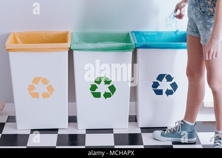 Kid werfen Sie eine Plastikflasche in ein blau bin. Kind recycling Bildung Konzept Stockfoto