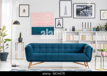 Bequem, blaue Couch in Weiß Wohnzimmer Interieur mit Bücherregal und Gemälden eingerichtet Stockfoto