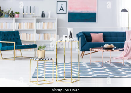 Kreativ, goldenen Hocker mit Pflanzen- und keramische Gefäße in einem Wohnzimmer mit Sessel und Sofa im Hintergrund Stockfoto