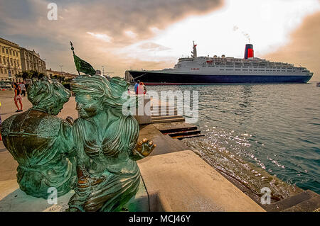 Italia, Friaul Julisch Venetien, Triest. Il Lato mare di Piazza Unità ospita La Scala Reale in cui si trova La statua in Bronzo raffigurante due Donne intente eine cucire La Bandiera italiana, l'Opera porta Il Nome di'Le Ragazze di Trieste". | Italien, Friaul Julisch Venetien, Triest. Eine Bronzestatue von Frauen nähen die italienische Flagge entlang der Uferpromenade Stockfoto