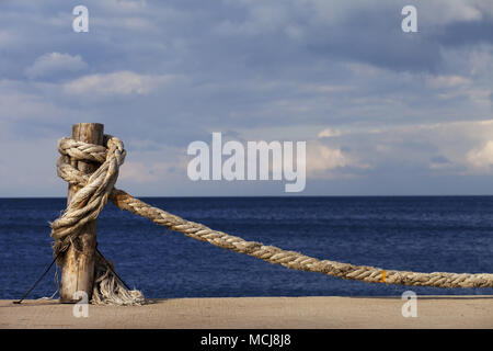 Alte Seil geknotet auf hölzernen Pfosten im Meer, blaues Meer und bewölkter Himmel, Sonne Sommer Tag. Türkei, Erdek, an der Küste des Marmarameers. Stockfoto