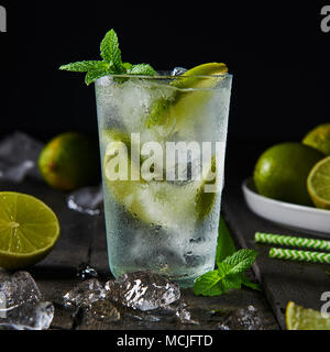 Mojito Cocktail mit Limetten und Minze in highball Glas mit Eis auf einem dunklen Hintergrund. Platz crop. Stockfoto