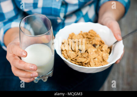 Mädchen mit einem Teller Müsli. Flakes aus Vollkorn mit getrockneten Früchten. Gesunde Ernährung Konzept. Ein Mädchen in Jeans und ein kariertes Hemd. Die richtige Ernährung. Uhr Stockfoto