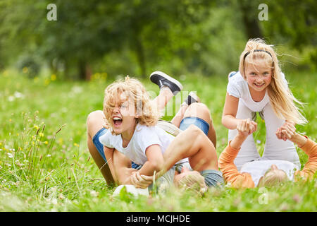 Lachen Geschwister Kinder spielen und toben mit ihren Eltern im Gras Stockfoto