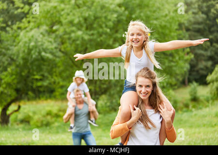 Glückliches Mädchen reiten Huckepack auf den Schultern der Mutter Stockfoto