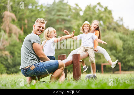 Vater spielt und Felsen mit Kindern auf dem Spielplatz im Park Stockfoto