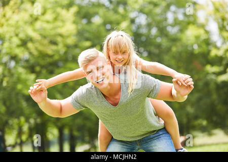 Mann spielt und tobt um mit seiner Tochter auf seinem Rücken in der Landschaft Stockfoto