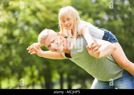 Der Mensch als glücklich Vater spielt mit seiner Tochter auf dem Rücken Stockfoto