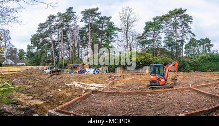 Orange Hitachi schwerem mechanische Digger in den Grundstein für ein neues Haus im Bau auf einer Baustelle in Surrey, Südosten, England, Grossbritannien Stockfoto