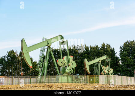 Zwei aktive pumpjacks Öl pumpen aus einer gut befindet sich im Zentrum von Frankreich unter einem blauen Himmel. Stockfoto