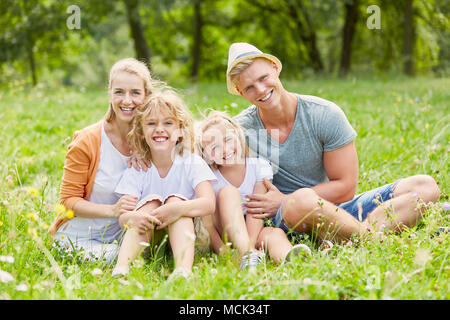 Happy Family ist sitzen gemeinsam im Sommer auf einer Wiese Stockfoto