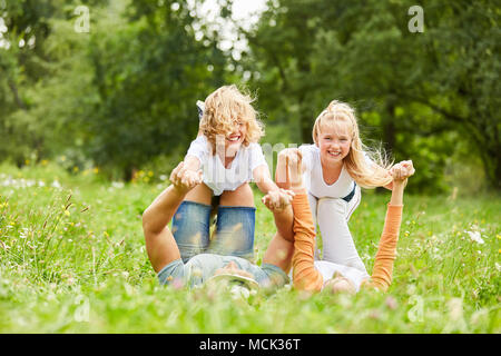 Geschwister Kinder und Eltern spielen zusammen auf einer Sommerwiese Stockfoto