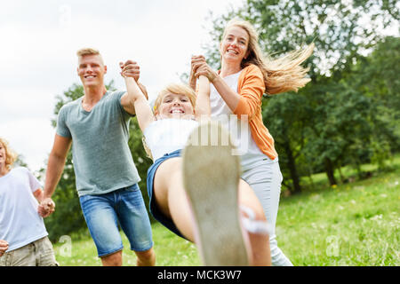 Die Eltern spielen und toben mit ihren Kindern im Sommer im Garten Stockfoto