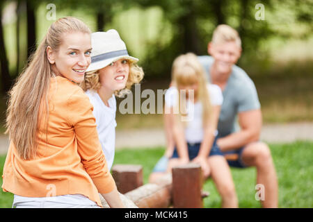Mutter und Sohn auf einer Schaukel mit Vater und Schwester in den Hintergrund Stockfoto