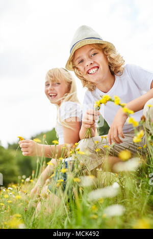 Geschwister Kinder Spaß haben Blumen pflücken auf einer Wiese Stockfoto