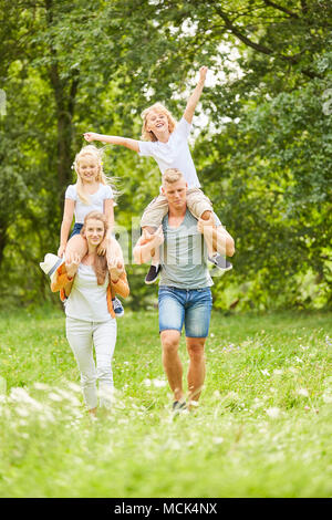 Die Eltern gehen auf eine natur ausflüge und ihre Kinder Huckepack Stockfoto