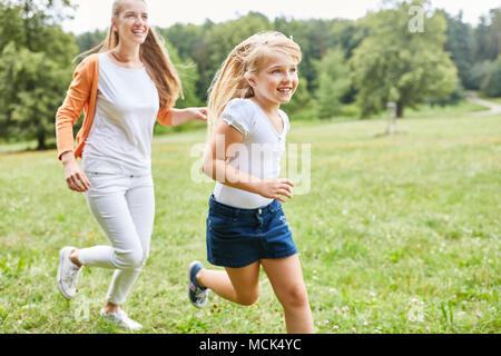 Mutter und Tochter machen ein Rennen auf einer Wiese im Sommer Stockfoto