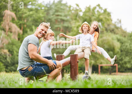 Glückliche Familie hat Spaß auf der Schaukel im Park im Sommer Stockfoto