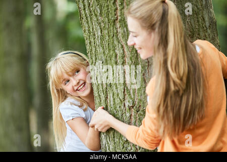 Blonde Mädchen spielen verstecken und in den Wäldern zusammen versuchen mit der Mutter Stockfoto