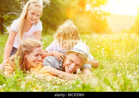 Glückliche Familie mit zwei Kindern liegt auf einer grünen Wiese während ihrer Sommerferien Stockfoto