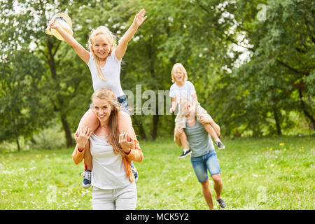 Happy girl ist reiten Huckepack auf Mutter zurück Stockfoto