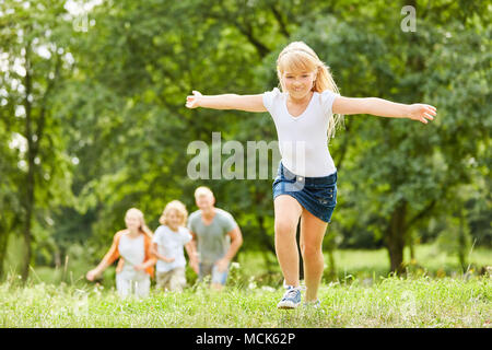 Fröhliche blonde Mädchen läuft und wütete in den Park während des Urlaubs Stockfoto