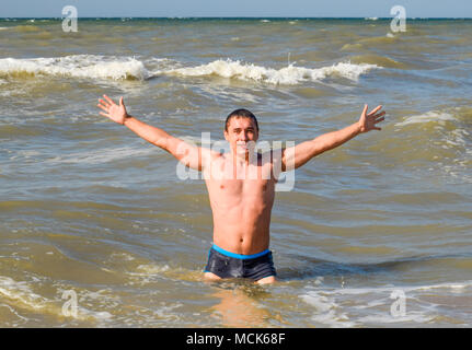 Sport Mann kommt aus dem Meerwasser. Baden im Meer. Ein Mann ist das Schwimmen unter den Wellen des Meeres. Stockfoto