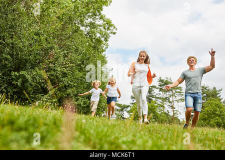 Familie und Kinder in den Sommerferien gerne laufen auf einer Wiese Stockfoto